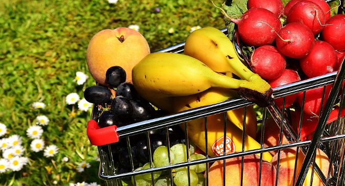 Small grocery cart holding grapes, bananas, peaches, and radishes