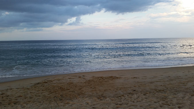 Beach looking out over a calm ocean with clouds