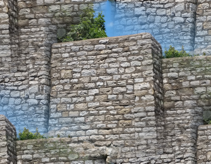 Photo of a stone wall that appears to be stacked in layers, highlighted by blue haze